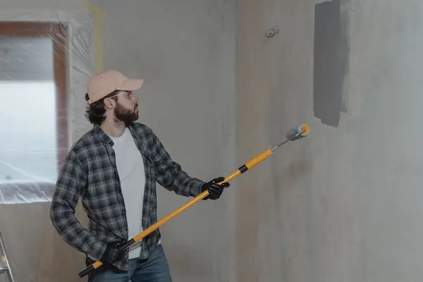 Painter rolling grey paint onto an interior wall in Springfield